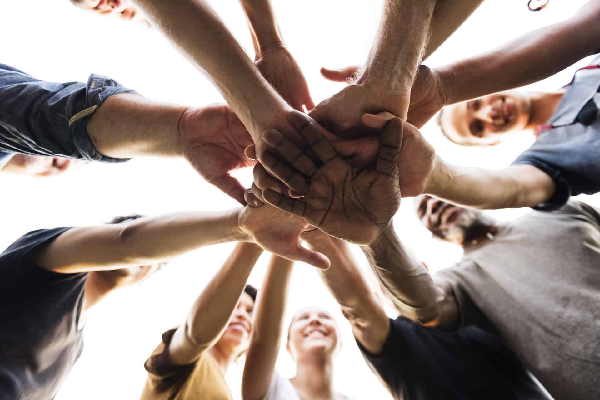 A team of colleagues join hands